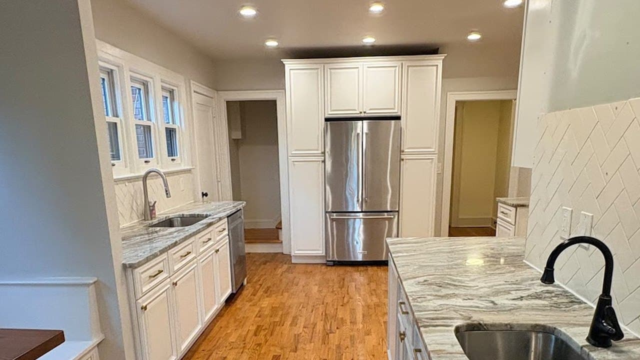 Spotless galley kitchen with white cabinets and granite counters